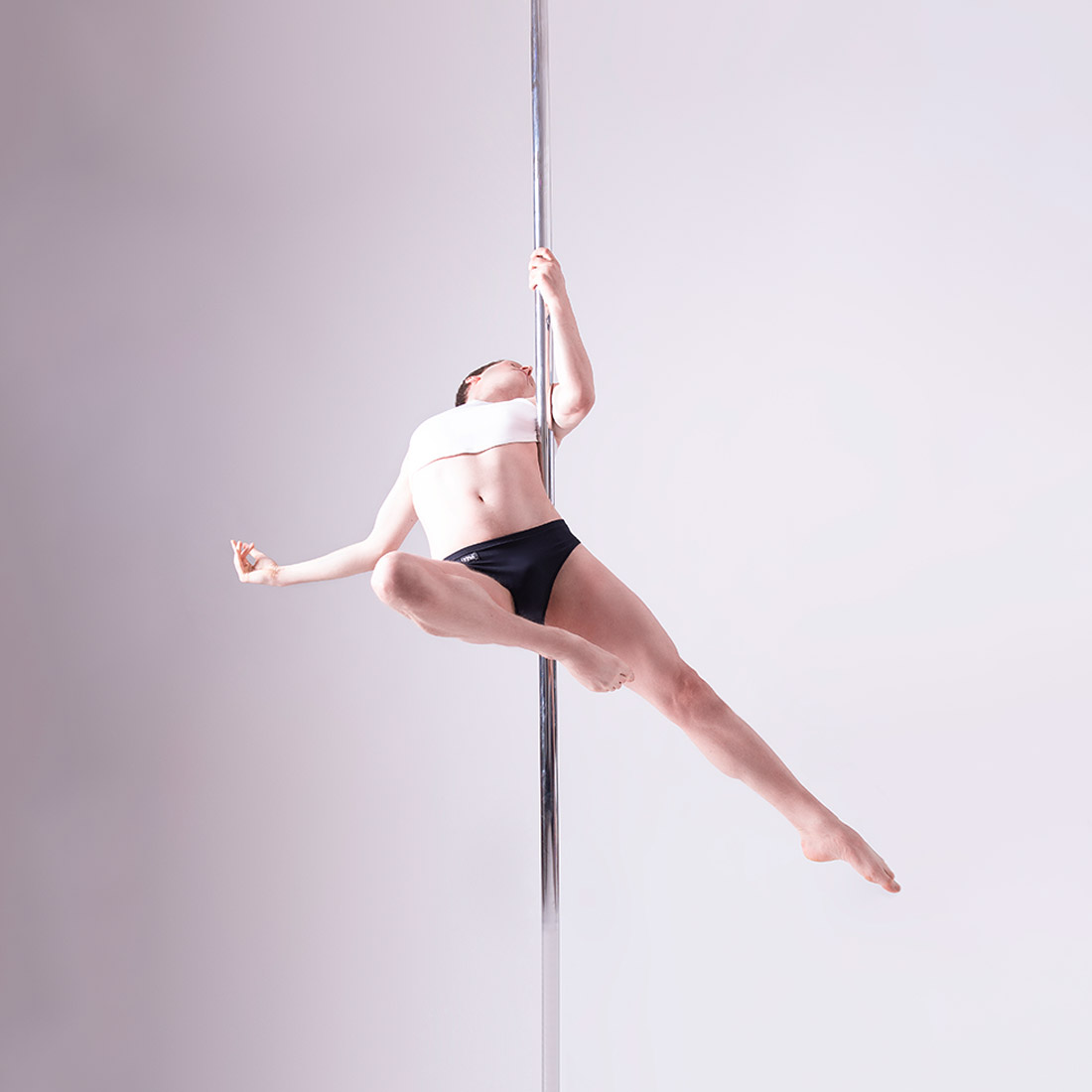 male pole dancing teacher performing spinning pole move in class at london dance academy